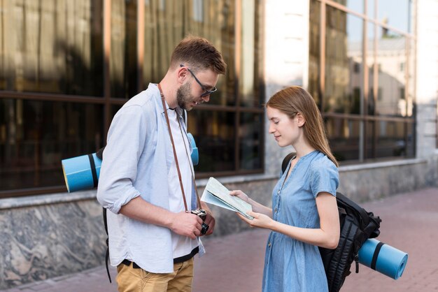 Side view of tourist couple with backpacks and map