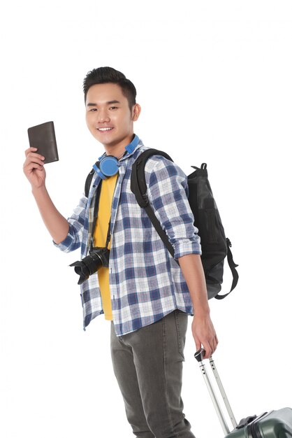 Side view of a tourist with carry on luggage ready to present his passport 