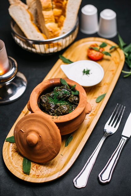 Side view a traditional azerbaijani dish dolma meat in grape leaves in a clay pot with yogurt