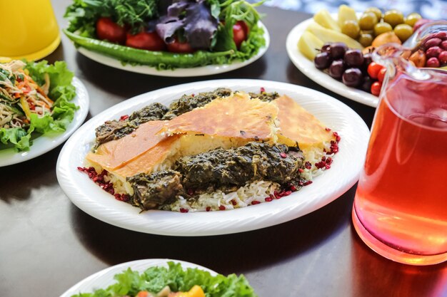 Side view a traditional azerbaijani dish syabzi pilaf meat with herbs and boiled rice on a plate with compote