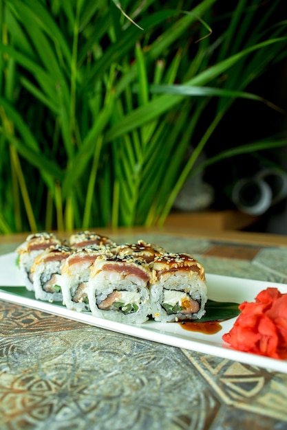 Free photo side view of traditional japanese cuisine sushi roll with eel avocado and cream cheese on green