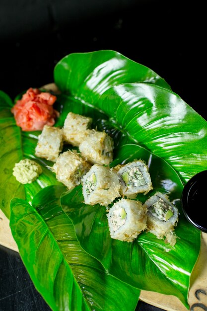 Side view of traditional japanese cuisine sushi roll with tuna served with ginger on green leaf