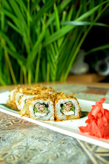 Side view of traditional japanese cuisine sushi roll with tuna served with ginger on green