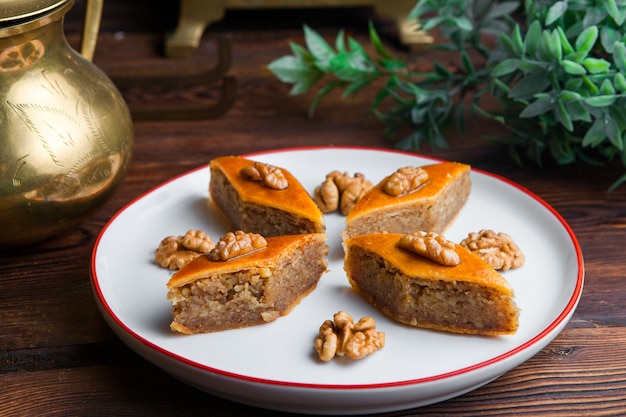 Free photo side view traditional oriental dessert baklava decorated with walnuts