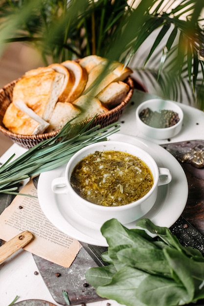 Side view of traditional russian green borsch with sorrel meat and eggs on a wooden board