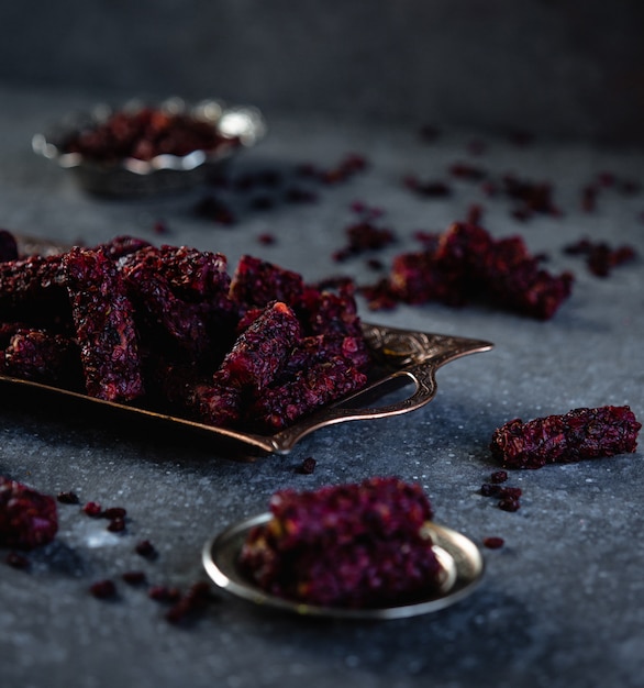 Side view of traditional turkish delight barberry lokum on antique silver tray on black wall