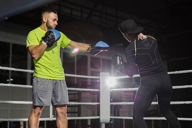 Side view of trainer and female boxer in the ring