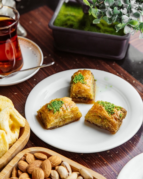 Боковой вид турецкой пахлавы с орехами и стаканом чая