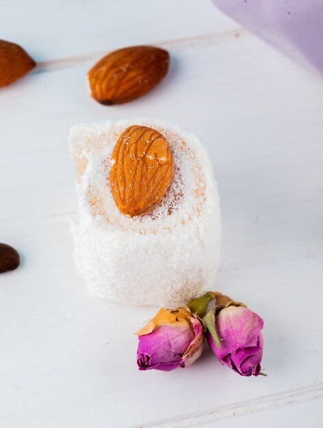 Side view of turkish delights rahat lokum and tea rose buds on a white background