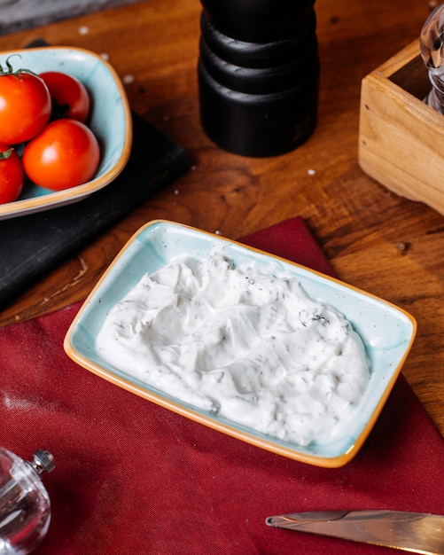 Free photo side view of turkish sauce cacik with herbs on a wooden table