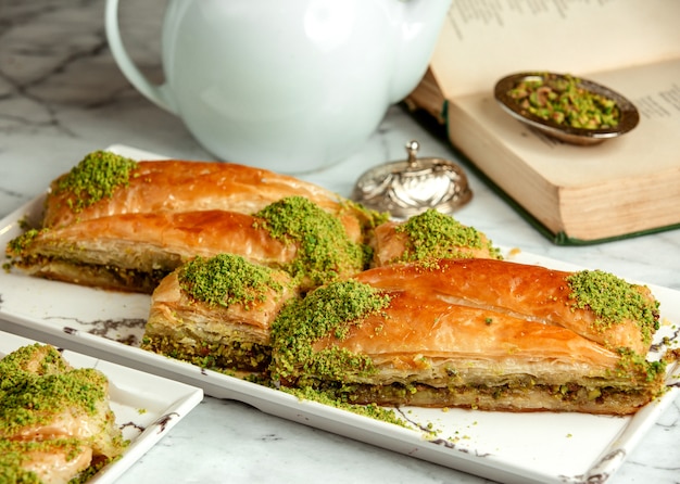 Side view of turkish sweets triangular shapedbaklava with pistachio on platter