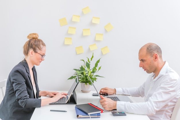 Side view of two businesspeople using laptop at workplace