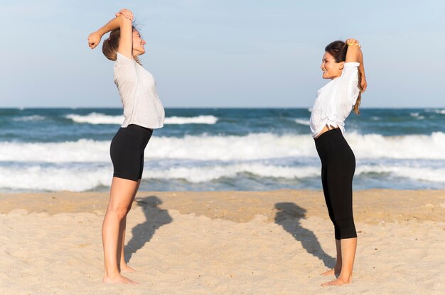 해변에서 운동하는 두 여자 친구의 측면보기