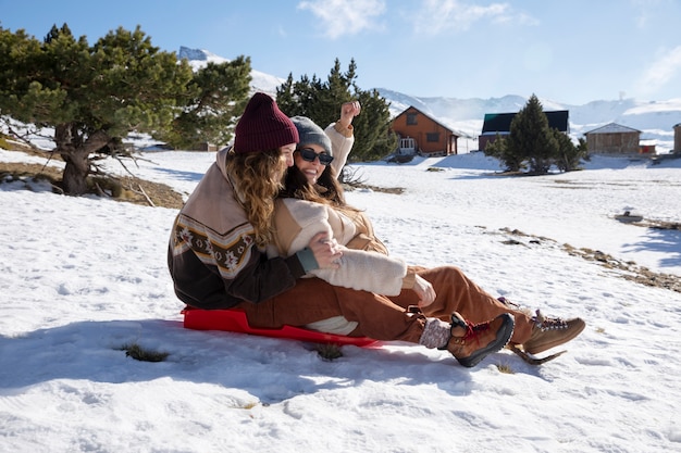 Side view of two female lovers on a sleigh during winter trip