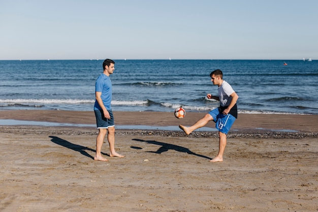 ビーチでサッカーをする2人の友人の側面図