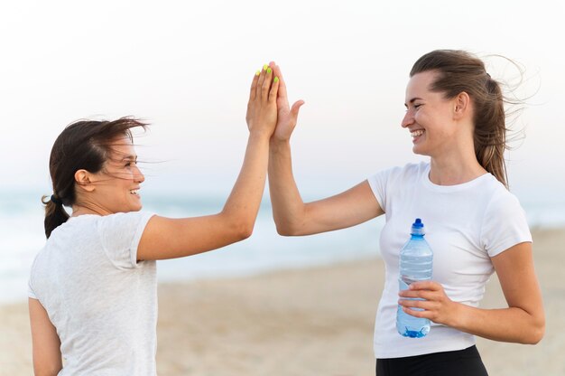 Side view of two women high-fiving each over