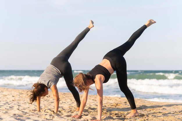 Side view of two women working out on the beach