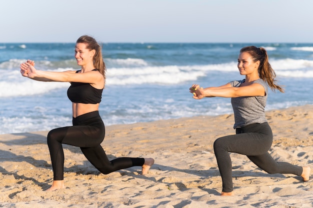 Side view of two women working out together on the beach