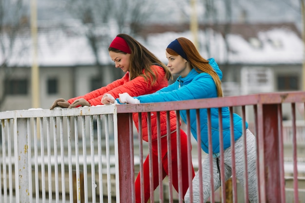 Free photo side view of two young female friend standing near the railing