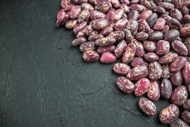 Side view of uncooked beans lined up on dark color background with free space