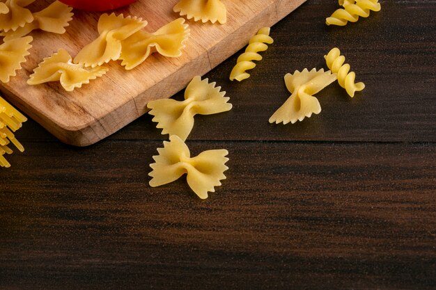 Side view of uncooked pasta on cutting board on wooden surface