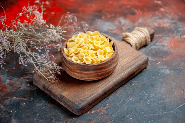 Side view of uncooked pastas on wooden cutting board on mixed color table