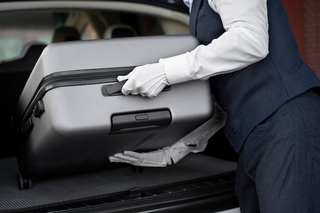 Free photo side view valet putting baggage in trunk