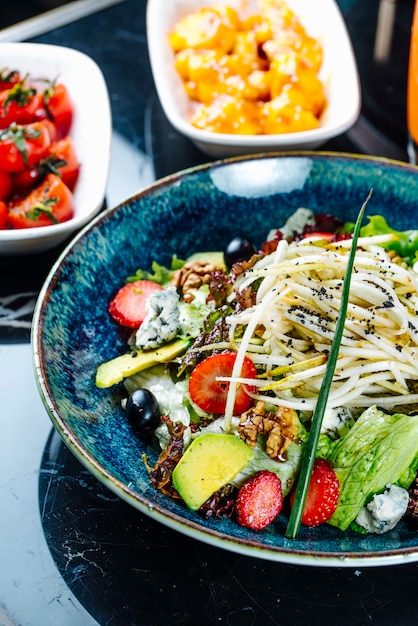 Insalata di verdure di vista laterale con le fragole e l'uva di frutta in un piatto