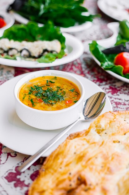 Side view of vegetable soup topped with herbs in a white bowl