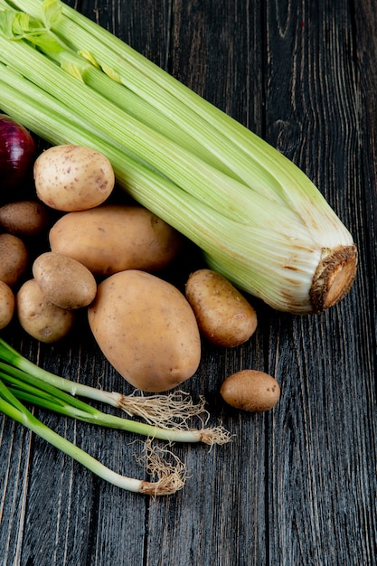 Вид сбоку овощей, как сельдерей, картофель и лук-шалот на деревянном фоне с копией пространства