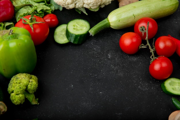 Side view of vegetables as pepper cucumber tomato zucchini and others on black background with copy space