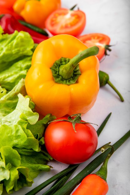 Side view of vegetables as pepper lettuce scallions on white surface