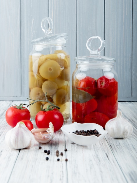 Free photo side view of vegetables as salted tomatoes garlic with black pepper on wooden surface and background