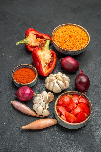 Side view vegetables onion garlic lentil bell peppers tomatoes spices on the black table