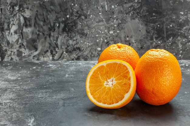 Side view of vitamin source cut and whole fresh oranges on gray background