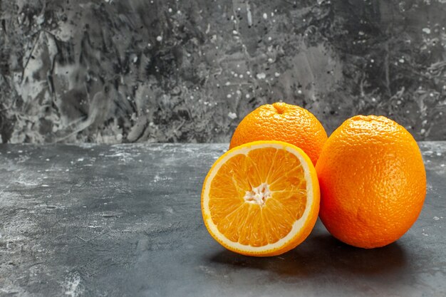 Side view of vitamin source cut and whole fresh oranges on gray background