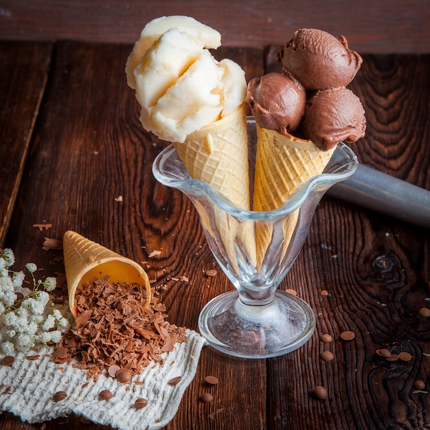 Вид сбоку вафельные рожки с шоколадным мороженым и ванильным мороженым и шоколадной стружкой в тряпичных салфетках