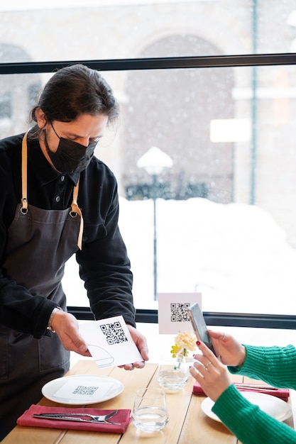 Side view waiter with mask holding qr code