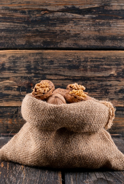 Side view walnuts in sack on wooden vertical