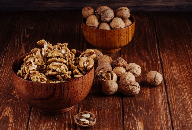 Side view of walnuts in a wooden bowl on dark rustic background