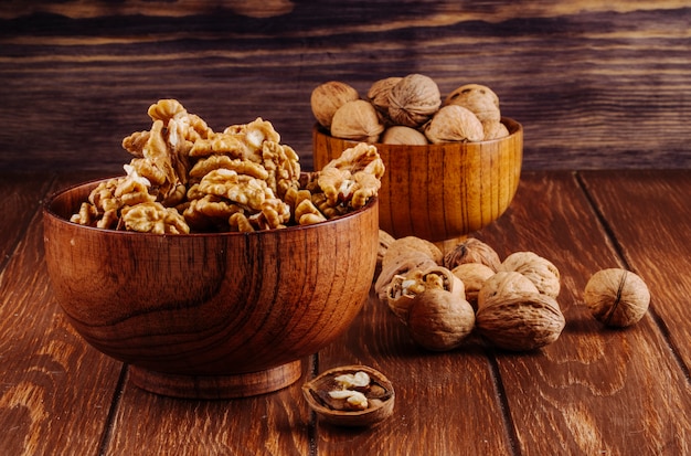 Side view of walnuts in a wooden bowl on dark rustic background