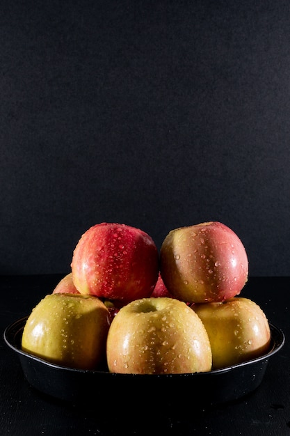 Side view wet apples in metal tray on black