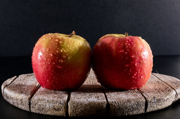 side view wet red apples on white wooden board on black  horizontal
