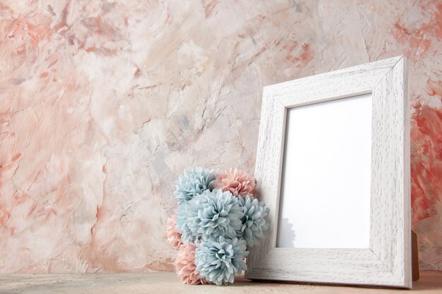 Side view of white empty wooden photo frame and flower on pastel colors surface