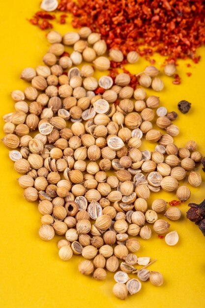 Side view of white peppercorns with dried chili pepper flakes on yellow background