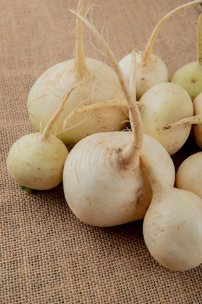 Free photo side view of white radishes on sackcloth background