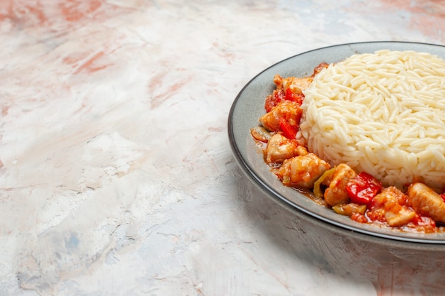 Side view of white rice meal with chicken and tomato