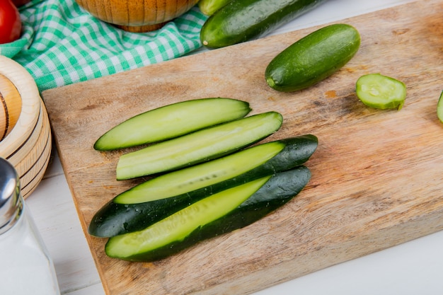 Free photo side view of whole cut and sliced cucumbers on cutting board