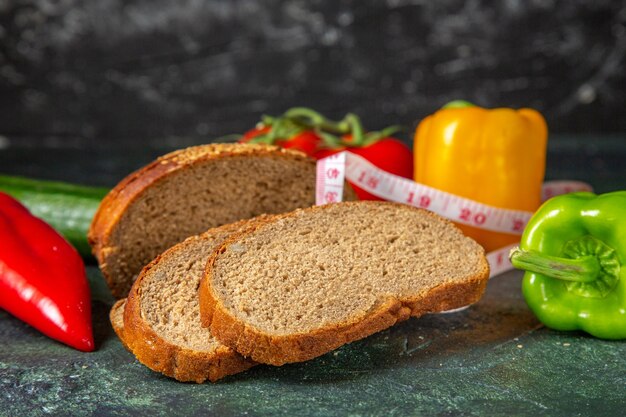 Side view of whole fresh organic vegetables and meter black bread slices