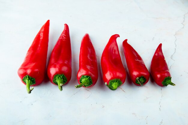 Side view of whole red peppers on white background